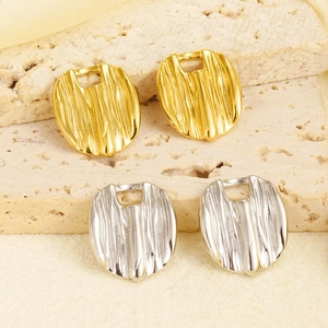 Detailed view of irregular textured gold and silver metal charms on a stone surface