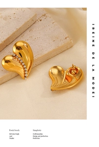 Macro shot of gold heart stud earrings with sparkling white crystals on beige stone