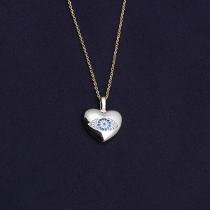 Goldene Herz-Halskette mit blauem Evil-Eye-Zirkon Anhänger auf blauem Stoffhintergrund