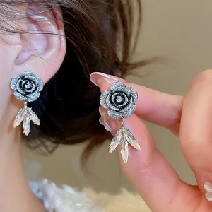 Dettaglio di orecchini a fiore in resina nera con cristalli per un look molto elegante