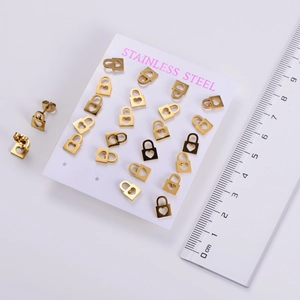 Detailed macro view of twelve pairs of gold stainless steel heart padlock stud earrings