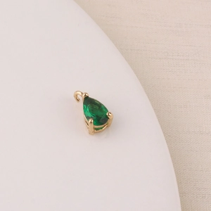 Detailed close-up of a pear-shaped green zircon pendant with gold plating for DIY jewelry
