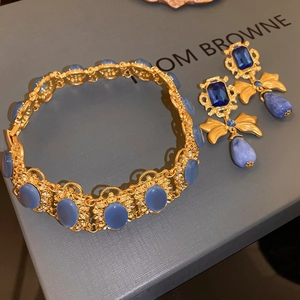 Detail of vintage gold bow earrings with blue stones and marble teardrops on a gift box