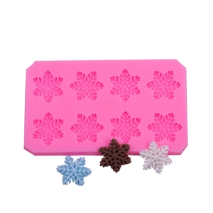 Rosa Silikonform mit 8 Schneeflocken-Motiven und fertigen Fondant-Schneeflocken