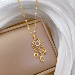 Close-up of golden dreamcatcher necklace with leaf pendants on luxury white silk