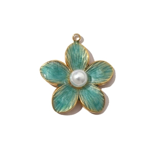Detailed shot of a green enamel flower pendant with gold trim and white pearl center
