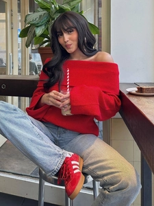 Pull en maille rouge chic à épaules dénudées pour femme avec un jean bleu clair