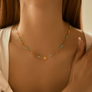 Evil eye beaded choker necklace with gold chain and colorful crystals worn by model