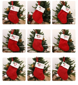 Detail of red knitted Christmas stockings with embroidered white initials and holly leaves