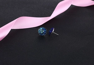 Macro shot of round S925 silver stud earrings with teal crystal clusters and pink ribbon