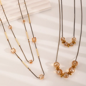 Detalle de collares de cristal ámbar en capas con toques dorados sobre un soporte blanco