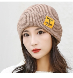 Close-up of brown knitted beanie with a yellow woven label and soft wool texture