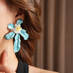 Détail d'une boucle d'oreille fleur en émail bleu avec perles jaunes portée par un mannequin
