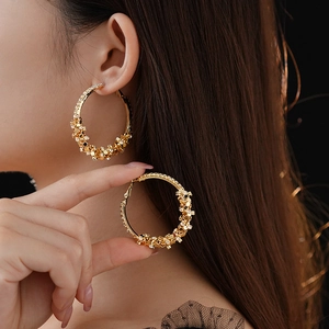 Gros plan de créoles dorées serties de strass étincelants portées par un mannequin chic