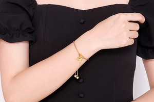 Détail d'un bracelet doré en titane avec pendentif clé en cœur porté au poignet