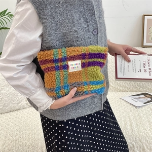 Detail of colorful plaid plush makeup bag with soft fleece texture and woven brand label