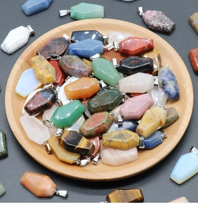 Assorted mini coffin pendants made of natural crystal stones on a wooden tray