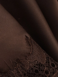 Detailed macro view of dark brown satin dress fabric with delicate lace trim