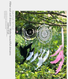 Detail of bohemian handmade dreamcatcher with feathers and lace hanging on a tree branch