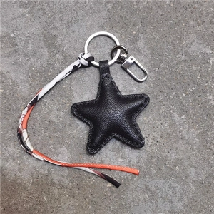 Close-up of black star leather keychain with patterned ribbon and metal clasp hook