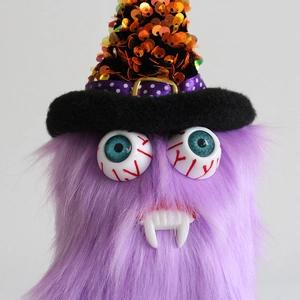 Halloween purple monster plush with sharp fangs and orange sequin wizard hat decor