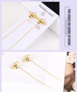 Detail of bee dangle earrings with gold plating, enamel wings and long chain tassels