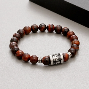 Detail of red tiger eye beads and metal skull charm on the elastic beaded bracelet