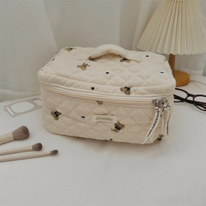 Quilted corduroy bear makeup bag detail with top handle and embroidery on white fabric