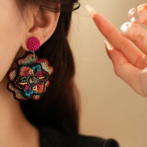 Detailed close-up of handmade floral embroidered earrings with colorful beads and sequins