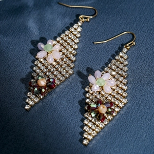 Detail of bohemian gold drop earrings with colorful floral accents and rhinestones