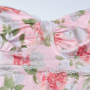 Detail of pink floral dress featuring white lace trim and satin fabric with rose print