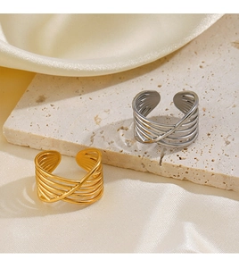 Detailed view of criss-cross layered gold and silver rings on silk and stone base
