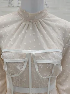 Detail of white corset dress with lace embroidery, sheer mesh neckline and puff sleeves