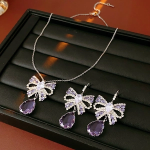 Detail view of silver bow jewelry set featuring purple teardrop gems and clear zircons