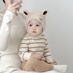 Detail showing plush cream winter baby earflap hat with cute ears and leather fashion tag