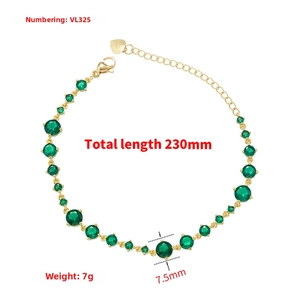 Detail view of gold chain bracelet with green zircon stones and heart charm extension