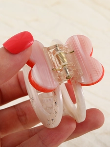 Detail of transparent acrylic hair claw with orange heart pattern and glitter finish