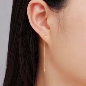 Detailed close-up of a gold S925 silver star and moon tassel earring on a model