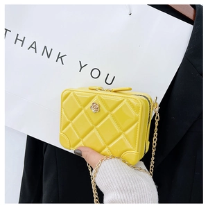 Detail view of yellow PVC jelly bag with quilted pattern and gold flower buckle