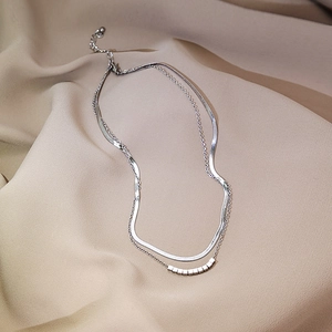 Close-up of layered silver snake chain necklace with small geometric square pendants