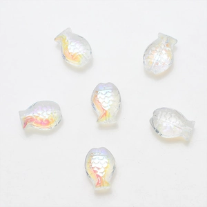 Macro detail of six translucent fish-shaped resin beads with iridescent scale textures