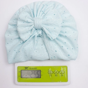 Light blue baby turban hat with large bow weighing 25.5g on a scale, breathable jacquard