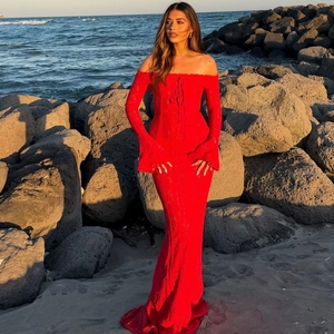 Detail of red off-the-shoulder lace dress with flared sleeves and slim fit tail at sunset