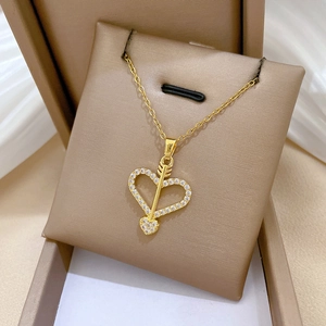 Macro shot of gold Cupid arrow heart necklace with crystals on soft silk cushion
