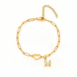 Detail of gold paperclip chain bracelet with zircon letter M and heart charm