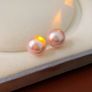 Macro shot of pink pearls with metallic luster on white velvet jewelry box background