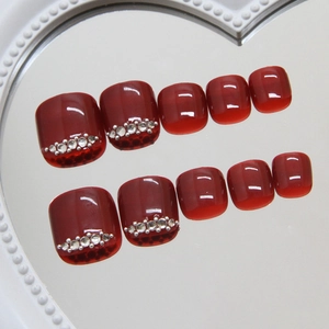 Deep burgundy press-on toenails with glossy jelly finish and sparkling rhinestones