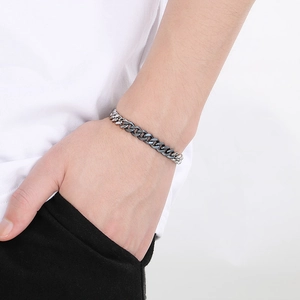 Polished silver stainless steel Cuban chain bracelet worn by a male model on wrist