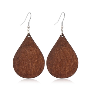 Macro shot of retro drop-shaped dark brown wood earrings with silver metal hooks