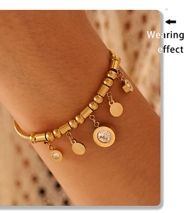 Close-up of gold beaded bracelet with Roman numeral ring pendant and clear zircon stone